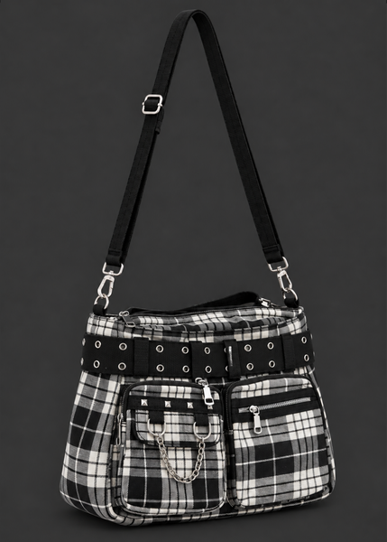 Angled view of a black and white plaid handbag showing front zip pockets, silver studs, chain detail and a black buckle belt.