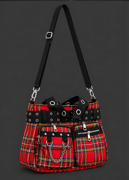 Angled view of a red tartan plaid handbag with an adjustable black shoulder strap, grommet handles and chain-trimmed front pocket.