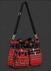Angled view of a red tartan plaid handbag with an adjustable black shoulder strap, grommet handles and chain-trimmed front pocket.