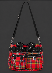 Front view of a red tartan plaid handbag with black grommet straps, zippered pockets, silver studs and chain detail.