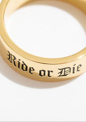Gold ring with 'Ride or Die' engraving on a white background