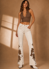 Woman wearing ivory cowhide flare jeans with brown crop halter top and white western boots – Rodeo Boot Cut by Pretty Attitude 

