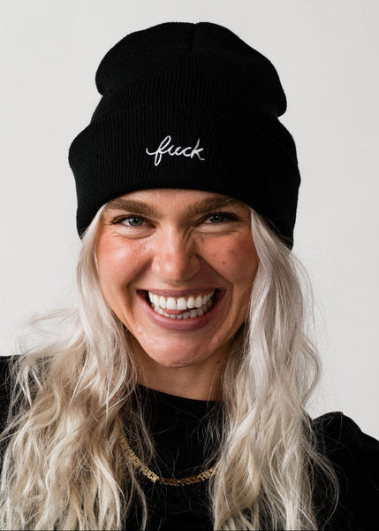 Person wearing a black beanie with white text on a plain background