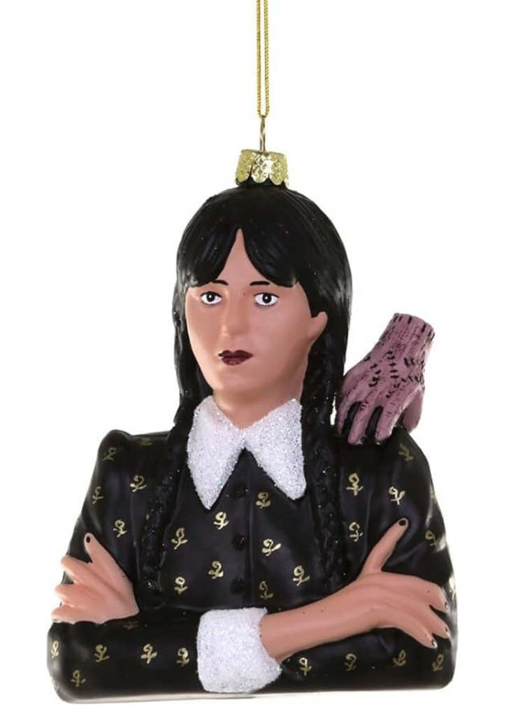 Decorative Wednesday ornament of a character with long black hair and a black outfit with gold accents on a white background.
