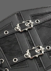 Close-up of a black leather accessory with two ornate silver-tone decorative buckles, silver grommets, and a textured patterned fabric background.