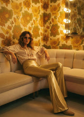 Woman wearing gold metallic bell bottom flare pants with cropped top at festival