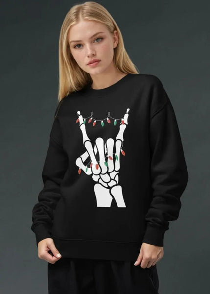 Person wearing a black sweatshirt with a skeleton hand design holding Christmas lights on a dark background