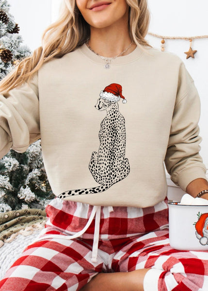 Person wearing a festive sweater with a snow leopard design and plaid pants, holding a mug with a Santa Claus design, in a cozy indoor setting.