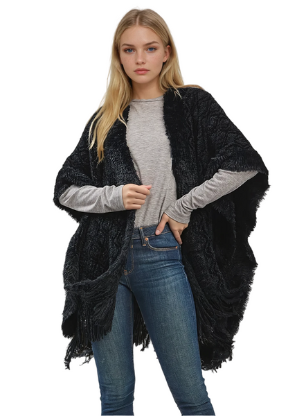 Woman wearing a black shawl over a gray sweater and blue jeans on a white background