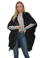 Woman wearing a black shawl over a gray sweater and blue jeans on a white background