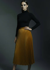 Full length shot of model wearing golden mustard velvet pleated skirt with black turtleneck

