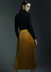 Close-up of golden velvet pleated midi skirt showing rich fabric texture and pleat detail
