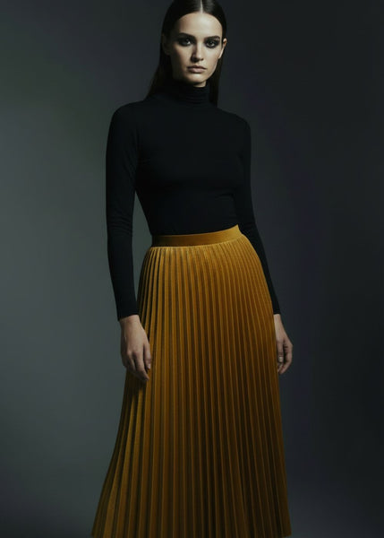 High waist accordion pleat velvet skirt in golden mustard worn by female model in studio
