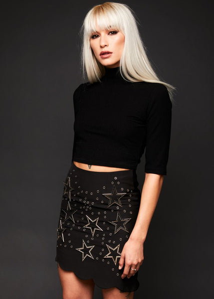 Back view of black studded mini skirt showing star studs and scalloped hemline detail
