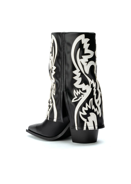 Close-up detail of black and white western pattern cowboy boots showing chunky heel and square pointed toe
